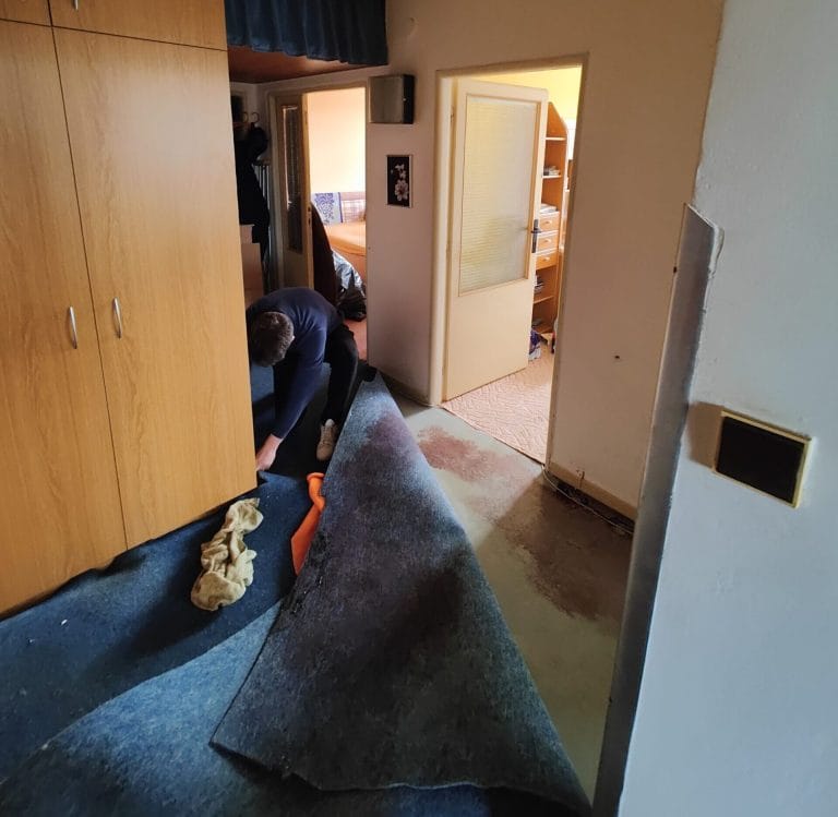 Muž při vyklízení bytu, odstraňování koberců a nepotřebných věcí.