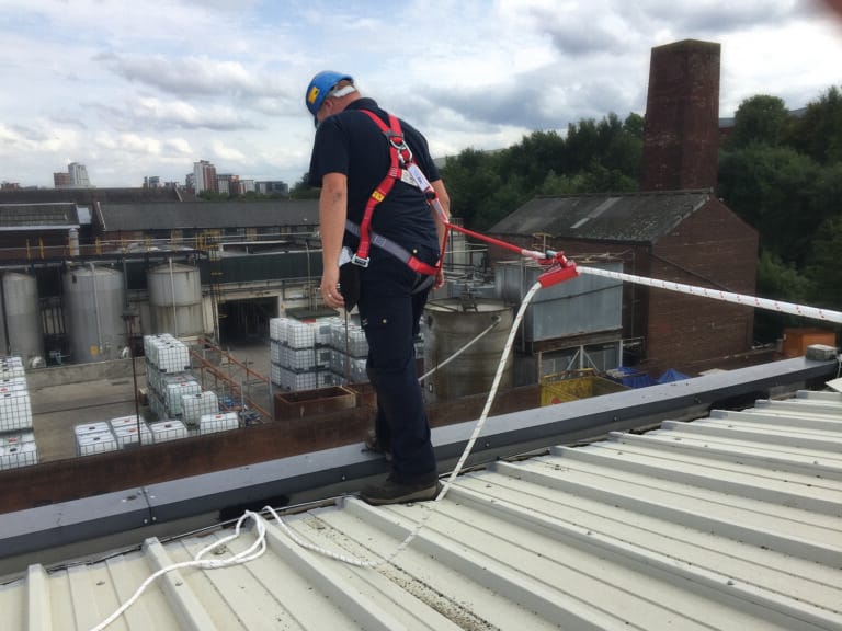 Muž v postroji na střeše - vyklízení a úklid průmyslových objektů.